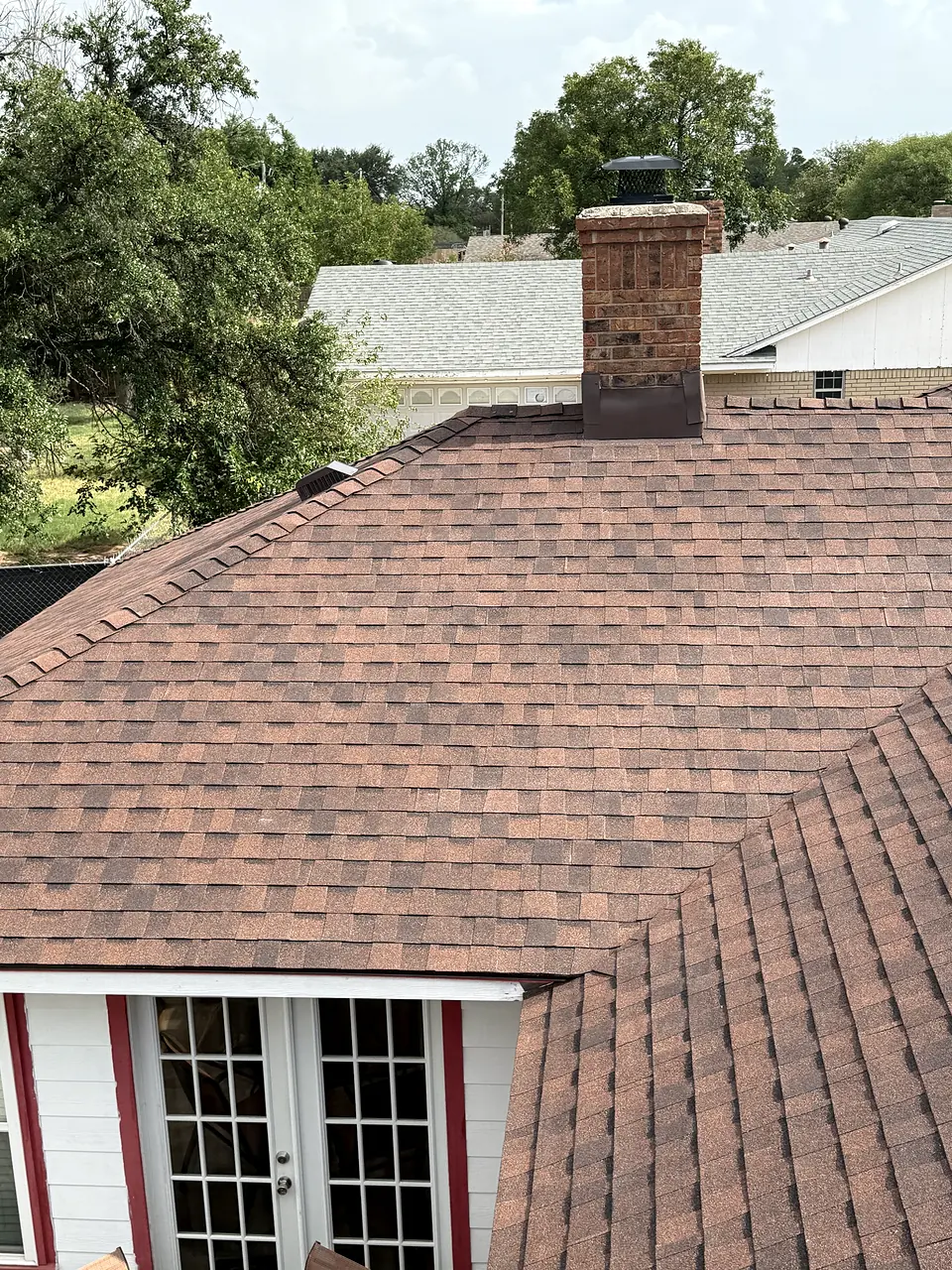 Reddish-brown asphalt shingle roof with a brick chimney
