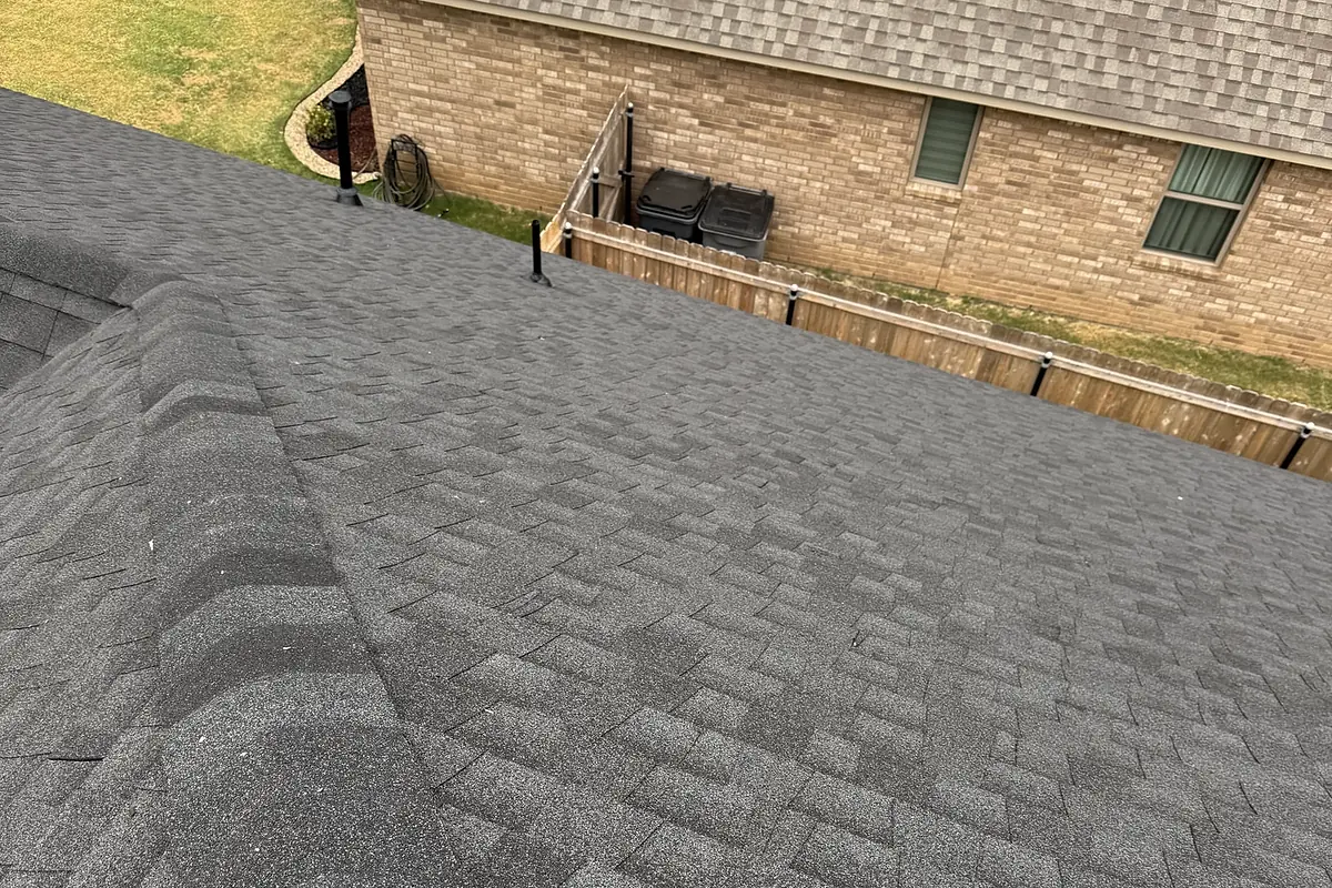 Residential roof shingles with vent pipes, viewed from the roof